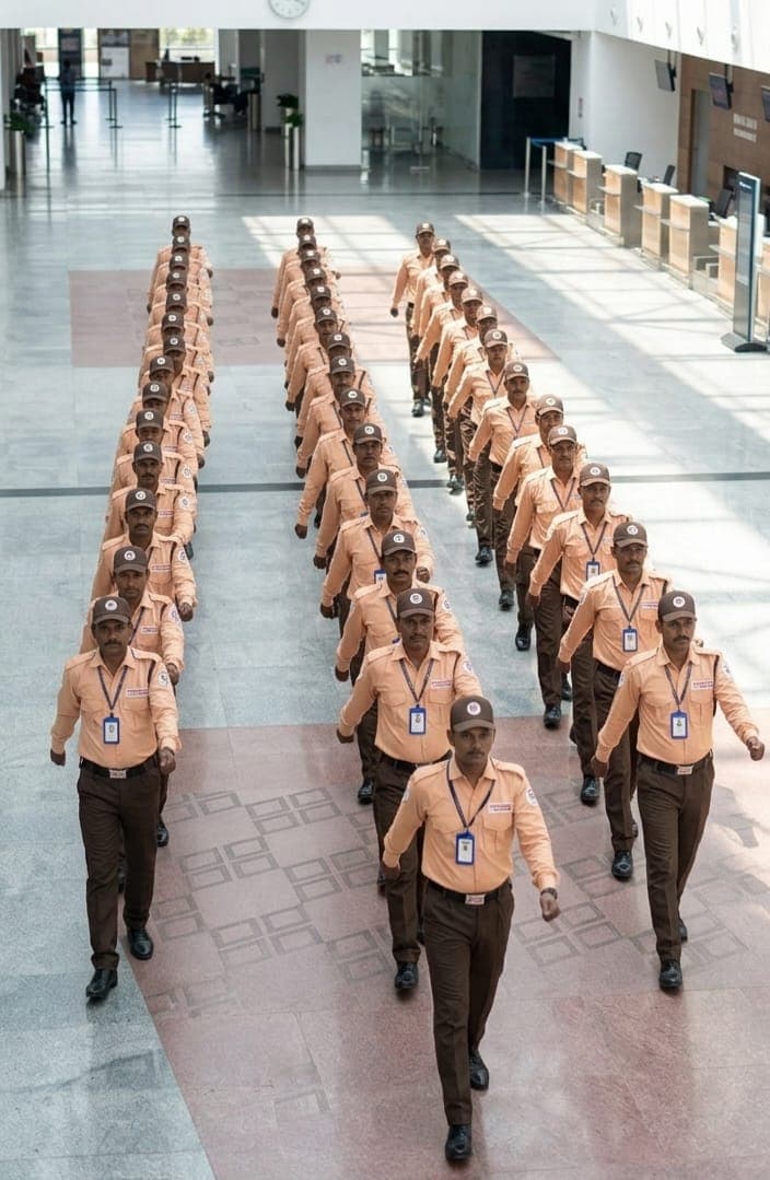 Security personnel in formation saluting during a formal outdoor ceremony